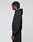 A person stands in profile against a plain light background, wearing the LIVE FAST DIE YOUNG Basic Hooded Zip and matching black pants. Their hair is styled in short twists, and their hands rest relaxed at their sides.