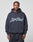 A man stands facing the camera in a dark blue LFDY Script Hooded sweatshirt from LIVE FAST DIE YOUNG, featuring “LivePart” in large script on the front. The oversized fit adds comfort and style against a light gray background.