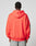 Seen from behind, a person with short curly hair wears the LFDY Angel Hooded sweatshirt by LIVE FAST DIE YOUNG in bright red, Oversize Fit, 100% cotton, with black print on one sleeve and loose light blue jeans. Hood is down; plain light background.