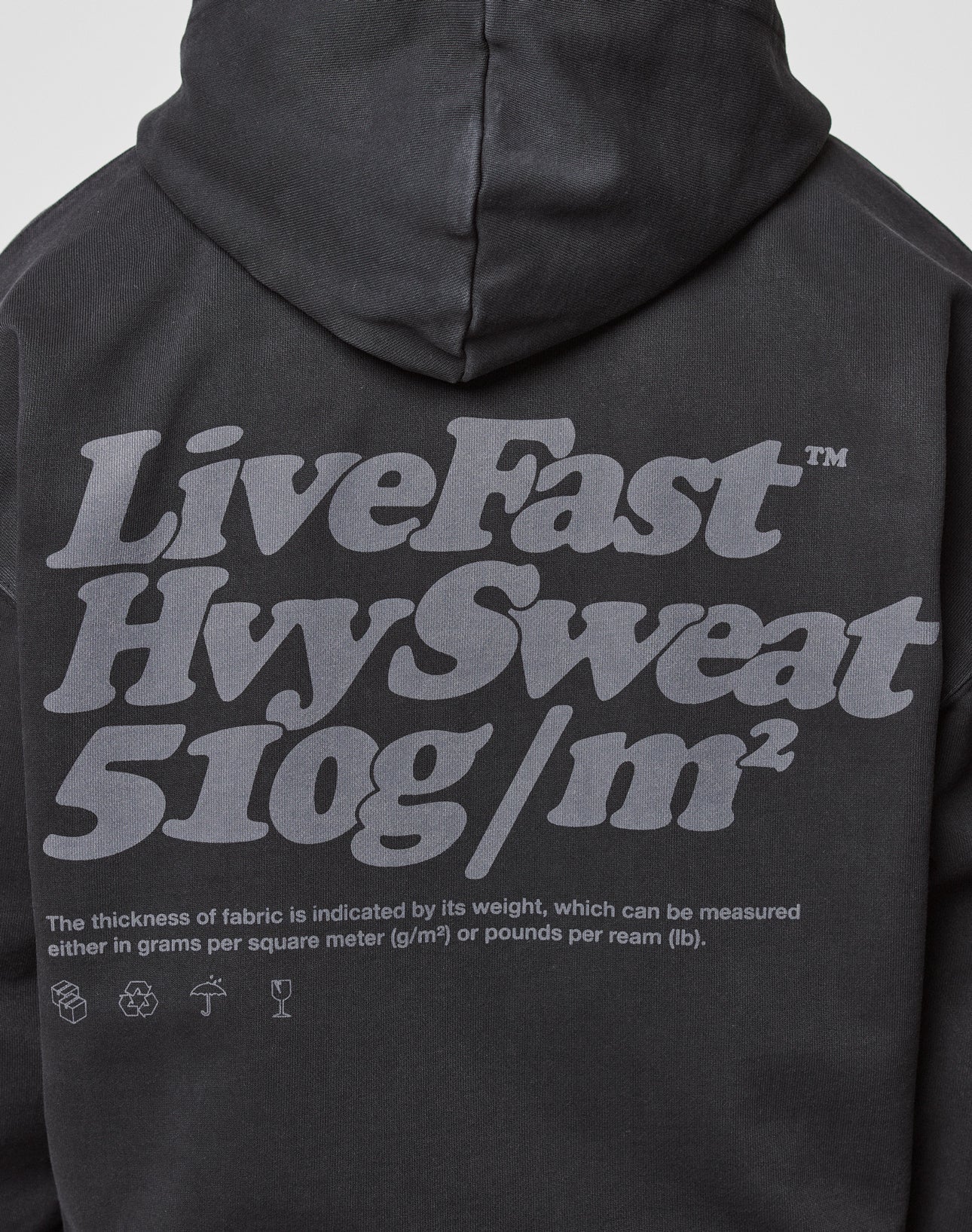 Back of a black Basic 510 Hooded Zip by LIVE FAST DIE YOUNG with bold gray LiveFast text, 510g/m² heavy fabric (85% Baumwolle), oversize fit, and a note explaining fabric thickness is measured in grams per square meter.