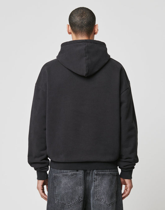 A person with short hair is seen from behind wearing the LIVE FAST DIE YOUNG LFDY The Bulldog Hooded and loose-fitting dark denim jeans, standing against a plain light gray background.