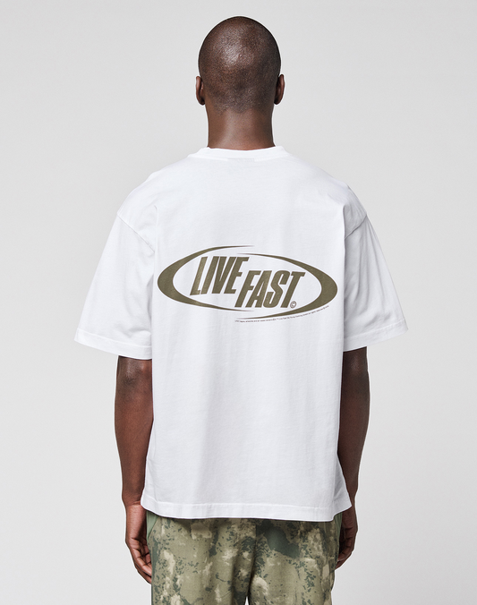 A person faces away, wearing the LIVE FAST DIE YOUNG LFDY Sphere Tee, an Oversize Fit white Baumwolle t-shirt with a bold “LIVE FAST” oval backprint, paired with green camouflage pants.