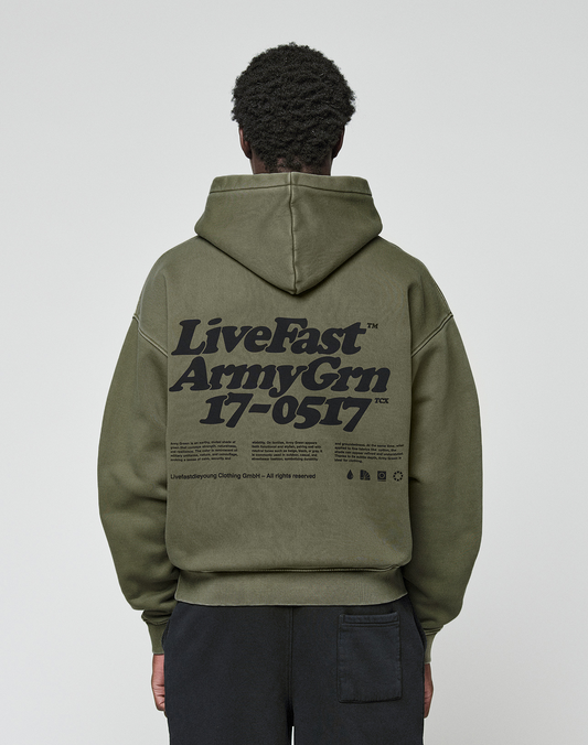 A person seen from the back wears the LIVE FAST DIE YOUNG Basic 360 Hooded in olive green, featuring oversize fit, large black “LiveFast Army Grn 17-0517” text, smaller details and visible topstitching. | model