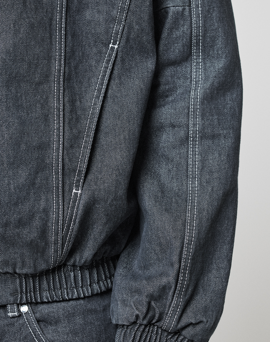 Close-up of a person wearing the LFDY Denim Trackjacket by LIVE FAST DIE YOUNG, made from 100% Baumwolle. Features include white stitching, an elastic waist, sleeve and pocket details, and a subtle Metall-Logo on the fabric.
