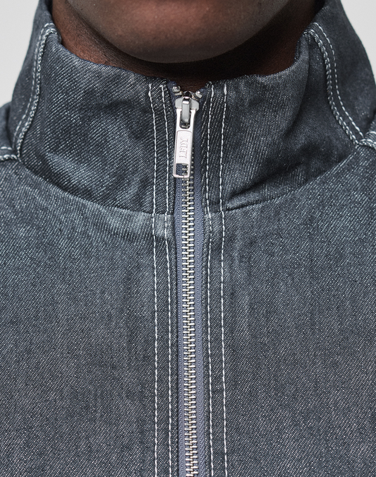 Close-up of a person wearing the LFDY Denim Trackjacket by LIVE FAST DIE YOUNG, featuring a Stehkragen, silver zipper, white stitching, and Metall-Logo detail, with only the lower half of the face and neck visible.
