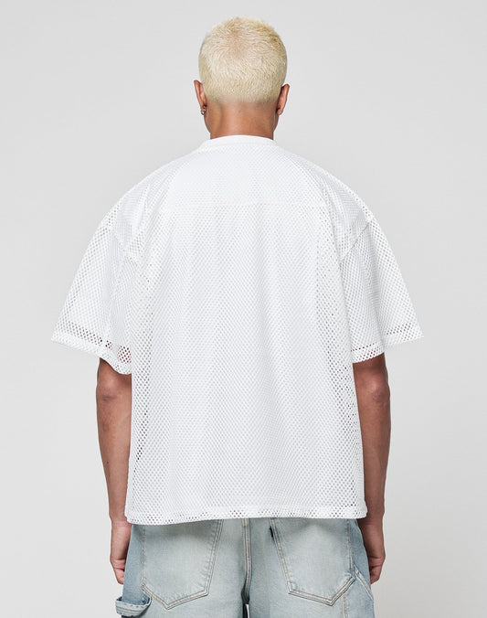 A person with short, bleached blonde hair is facing away, wearing the LIVE FAST DIE YOUNG LFDY Boxy Jersey—a loose white mesh short-sleeve shirt—paired with light blue distressed denim shorts against a plain gray background.