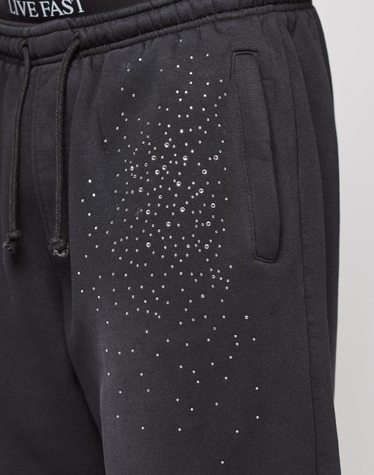 The Live Fast Rhinestone Jogger by LIVE FAST DIE YOUNG features black sweatpants with an elastic waistband, side pocket, rhinestone Muster on the upper thigh, partially visible "LIVE FAST" text, and a wide fit for comfort.