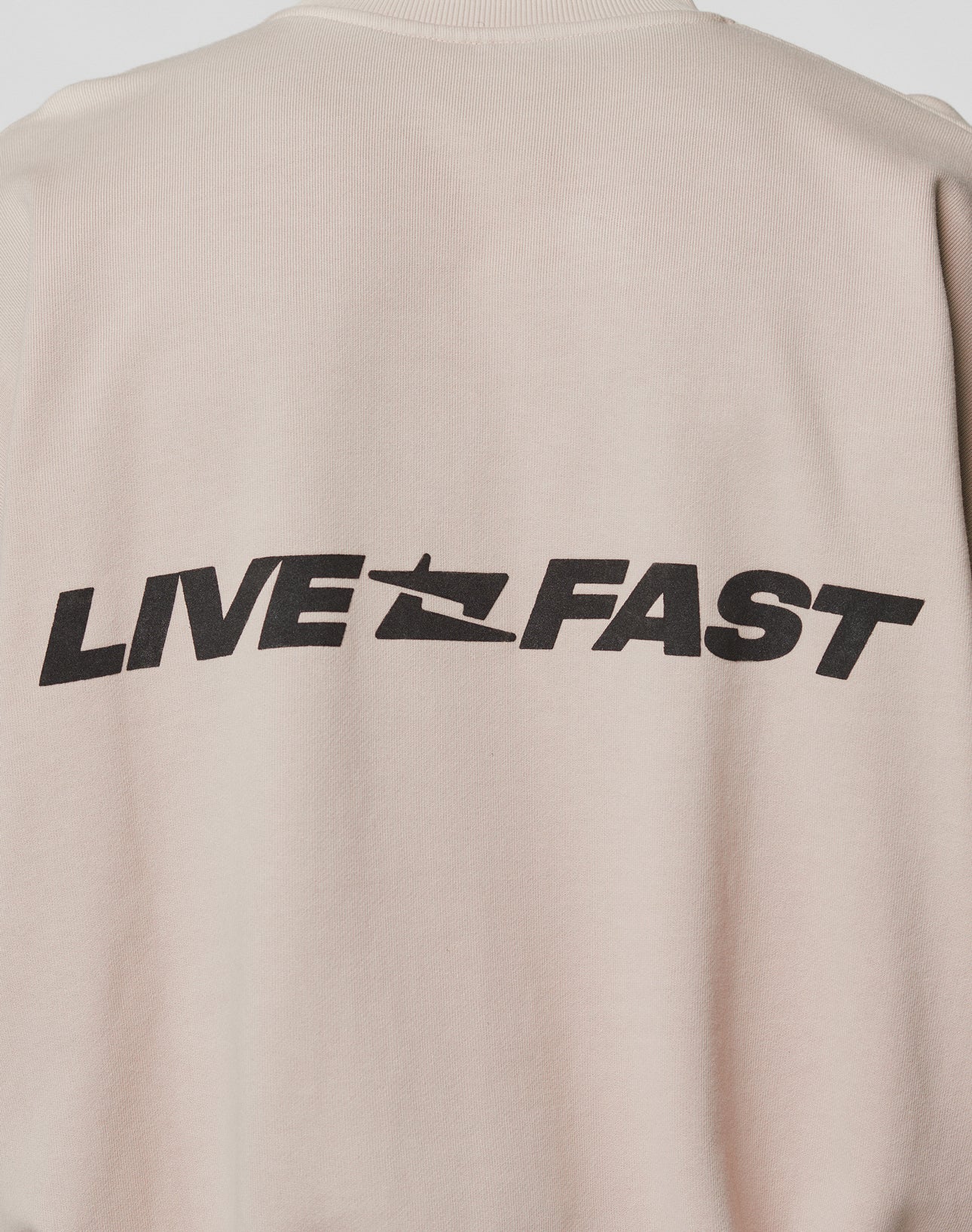 The Live For It Sweater by LIVE FAST DIE YOUNG is a beige oversized fit made from 100% cotton, featuring bold black LIVE FAST text and a stylized speeding graphic on the back.