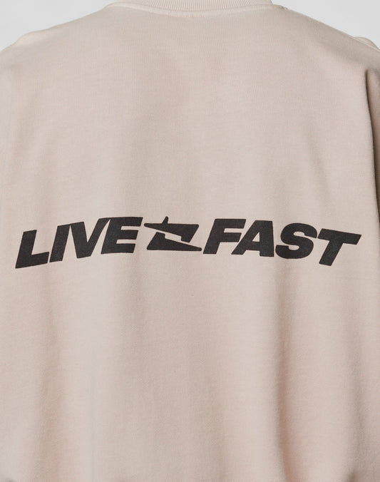 The Live For It Sweater by LIVE FAST DIE YOUNG is a beige oversized fit made from 100% cotton, featuring bold black LIVE FAST text and a stylized speeding graphic on the back.
