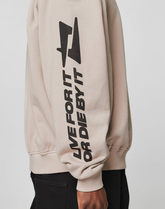 A person wearing the LIVE FAST DIE YOUNG Live For It Sweater in beige, featuring bold black LIVE FOR IT OR DIE BY IT text and a lightning bolt on the sleeve. Made from 100% Baumwolle for superior comfort.