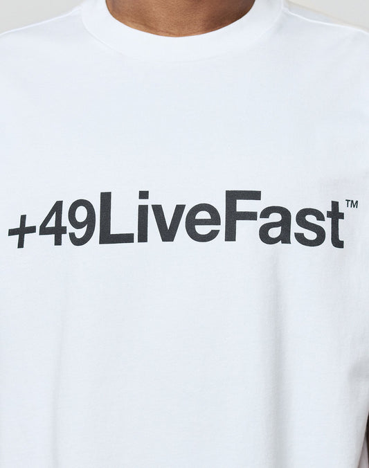 A close-up of a person wearing the Basic +49 Tee by LIVE FAST DIE YOUNG, an oversize fit white t-shirt featuring bold black +49LiveFast™ front print, crafted from 100% Baumwolle for ultimate comfort.