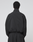 A person with short, curly hair stands with their back to the camera, wearing the black LIVE FAST DIE YOUNG LFDY Dealership Trackjacket and matching Regular Fit pants against a plain light gray background.