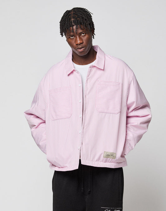 A man wearing the LIVE FAST DIE YOUNG LFDY Striped Padded Shirt with large front pockets, styled over a white shirt and black pants, stands against a plain light background.