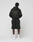 A person faces away, wearing the LIVE FAST DIE YOUNG Basic 360 Hooded black hoodie with "Live Fast Army Gn 17-051" back print, paired with black shorts, white socks, and white sneakers against a plain light background.