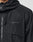 Close-up of the Live Fast Nylon Jacket by LIVE FAST DIE YOUNG, featuring a black, crinkled fabric with a hood and zipper. A gray LIVE FAST Silikon-Print appears on the chest. Only part of the wearer’s neck and jaw is visible. Oversized fit.