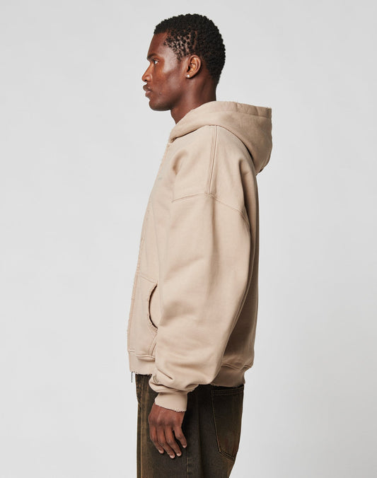 A person stands in profile facing left, wearing the LFDY Double Hooded Zip by LIVE FAST DIE YOUNG and dark pants against a plain light background.