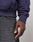 A close-up of a person’s hand at their side, wearing the LIVE FAST DIE YOUNG Live Fast Stallion Hooded sweatshirt in dark purple Baumwolle and gray denim jeans, with a neutral, blurred background.