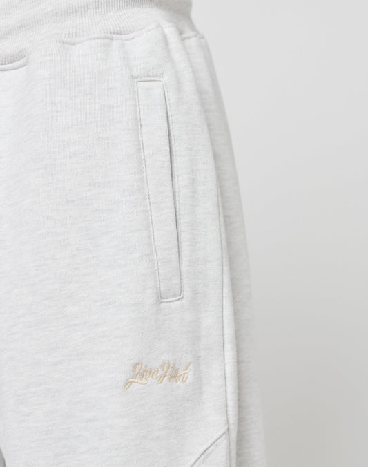 Close-up of the LIVE FAST DIE YOUNG Basic Wide Jogger in light gray, featuring a vertical pocket and beige “Love Poet” embroidery near it, plus a comfortable elastic waistband, shown against a plain white background.