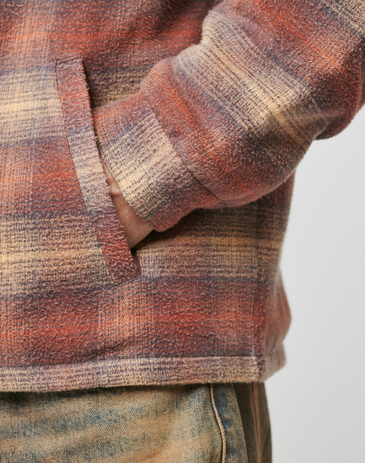 Wearing the LIVE FAST DIE YOUNG Vintage Padded Flannel in an oversized plaid red, purple, and beige with a hand in the pocket, paired with vintage wash faded blue jeans.