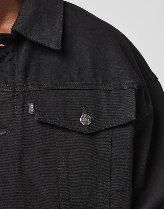 Close-up of the upper part of the LFDY Denim Jacket by LIVE FAST DIE YOUNG, made from 100% cotton with a metal button, small fabric tag on the chest pocket, pointed collar, and visible stitching.