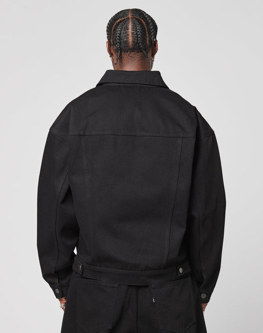 A person with neatly braided hair is shown from behind, wearing an oversize fit black LFDY Denim Jacket by LIVE FAST DIE YOUNG and matching black pants against a plain light background.