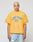 A person with short bleached blonde hair wears the LFDY Boxy Jersey by LIVE FAST DIE YOUNG, a yellow mesh T-shirt with blue LIVE FAST D(Y) lettering, paired with light blue ripped jeans against a plain background.