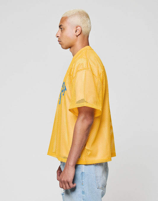 A person with short, bleached blonde hair wears the LIVE FAST DIE YOUNG LFDY Boxy Jersey and light blue jeans, standing in profile against a plain light gray background.