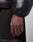 A close-up of a hand and wrist wearing a water-repellent, 600er Fillpower Live Fast Down Jacket by LIVE FAST DIE YOUNG with elastic cuffs, styled with relaxed black pants with bold white lettering.