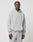 A man wears the LIVE FAST DIE YOUNG Basic Blank Hooded, a light gray oversize-fit hoodie with front pocket and matching sweatpants, made from soft cotton and polyester, standing against a white background with a neutral expression.