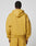 A person with short hair is seen from behind wearing the LIVE FAST DIE YOUNG Live Fast Sweatsuit Jacket in mustard yellow, featuring an oversized fit, large hood, and dropped shoulders. The background is plain and light-colored.
