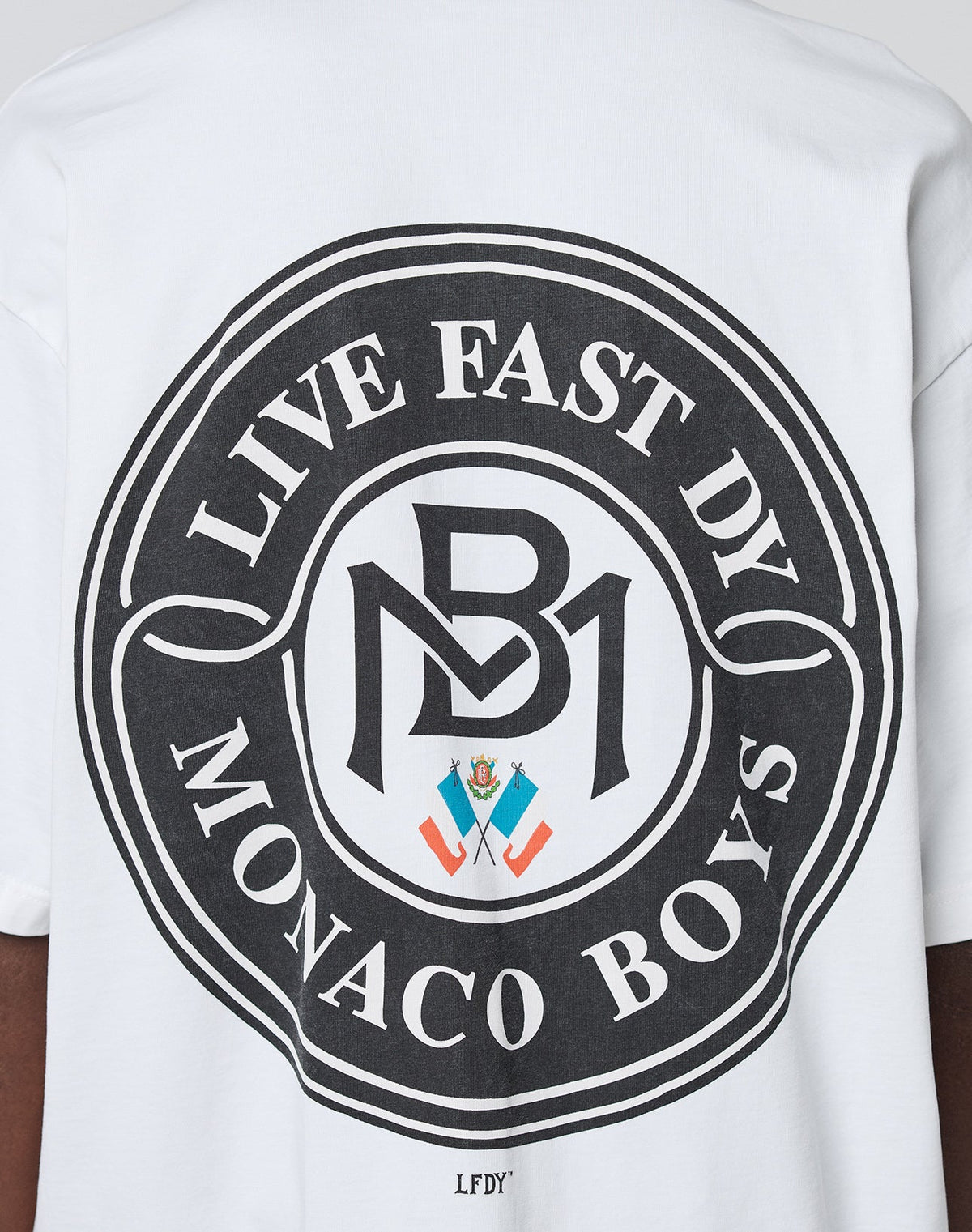 The LFDY Monaco Boys Tee by LIVE FAST DIE YOUNG features a large circular black graphic, LIVE FAST DY MONACO BOYS, bold MB logo, and colorful crest on the back. Made from 100% Baumwolle in an Oversize Fit for comfort and style.