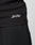 Close-up of a person in slim fit black pants and the LIVE FAST DIE YOUNG Basic Rib Tank, made from cotton and elastane, featuring Live Fast embroidered in white cursive near the hem.