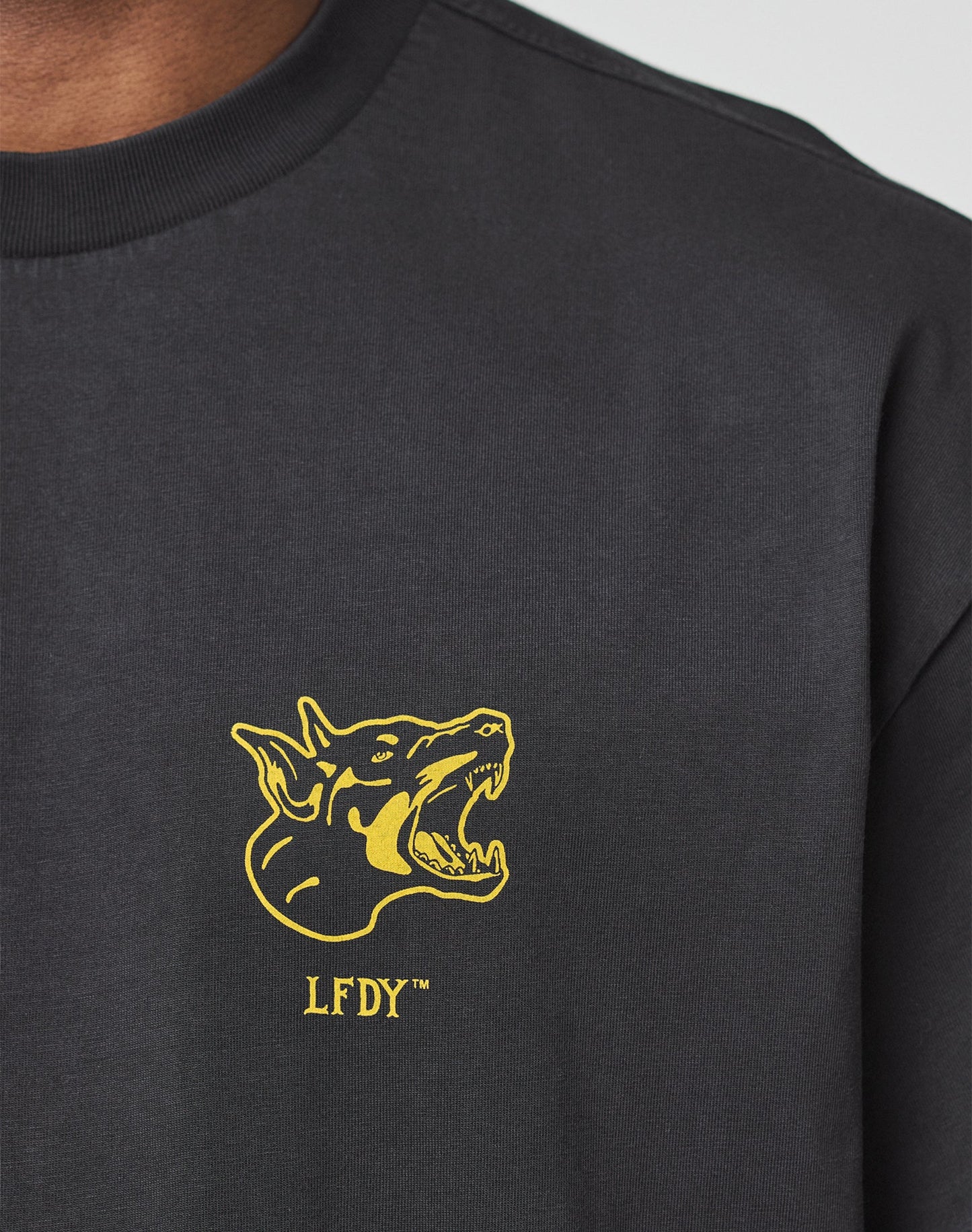 The LFDY Circle Dog Tee by LIVE FAST DIE YOUNG is a black Oversize Fit shirt with a yellow snarling dog graphic and LFDY lettering on the left chest, crafted from 100% Baumwolle for comfort.