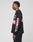 A person with short, twisted hair stands in profile against a plain background, wearing the LFDY Racing Longsleeve by LIVE FAST DIE YOUNG: an oversize black shirt made from 100% Baumwolle with white/pink graphics and reflective prints on sleeves and chest.