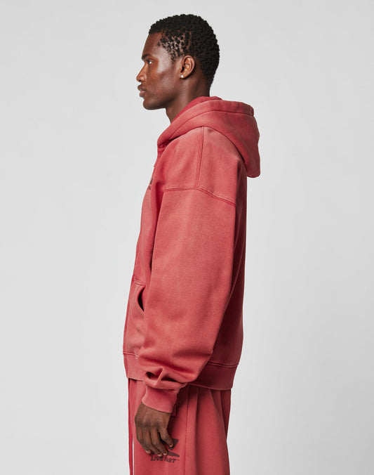 A person stands in profile wearing the LIVE FAST DIE YOUNG Live Fast Sweatsuit Jacket, a matching faded red, oversize fit piece with a vintage wash, set against a plain light gray background.