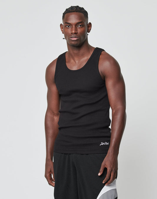 A man with short, braided hair models the LIVE FAST DIE YOUNG Basic Rib Tank in black, paired with black athletic shorts featuring white and gray details, standing against a plain light background and looking at the camera.