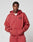 A person wears an oversize Live Fast Sweatsuit Jacket by LIVE FAST DIE YOUNG in red with hands in pockets, featuring a small black graphic and the words LIVE FAST on the chest.