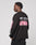 A person stands sideways, wearing the LFDY Racing Longsleeve by LIVE FAST DIE YOUNG. The black, oversize-fit shirt features pink and gray graphics and DIE YOUNG Everything in text on the back against a plain, light background.