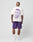 A man faces away, wearing the LFDY Originals Tee by LIVE FAST DIE YOUNG—a white oversize Baumwolle shirt with a bold purple backprint portrait—paired with purple shorts, white LIV socks, and white sneakers against a plain light background.