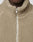 Close-up of a person wearing the beige LFDY Teddy Jacket by LIVE FAST DIE YOUNG in Oversize Fit, featuring a partially zipped silver zipper. Only the lower half of their face and neck are visible.