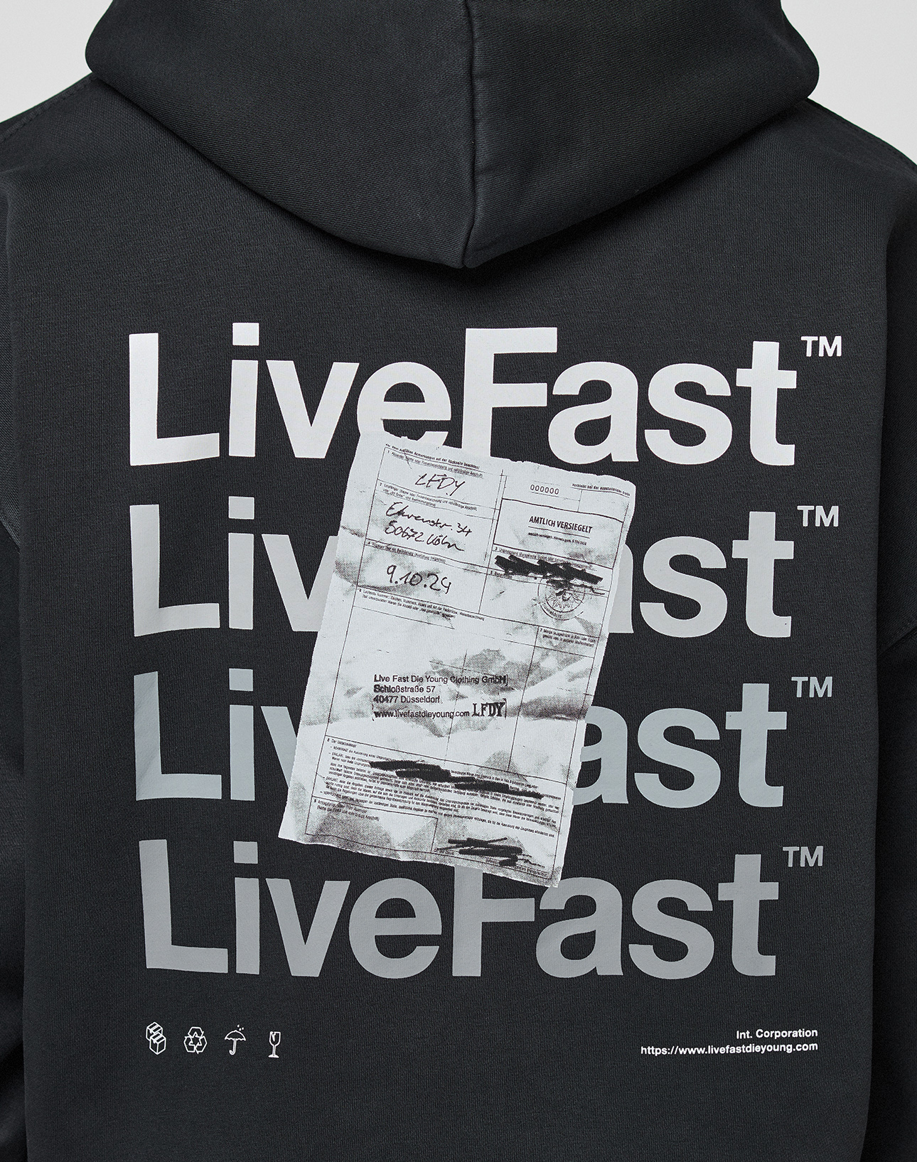 The Basic Evidence Hooded Zip by LIVE FAST DIE YOUNG is a black, oversized hoodie featuring repeated white LiveFast™ text and a printed document image on the back, small symbols, LFDY branding, and a website link at the bottom right.