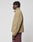 A person with short dreadlocks stands in profile, wearing the beige LFDY Teddy Jacket from LIVE FAST DIE YOUNG with maroon oversize-fit pants, set against a plain white background.