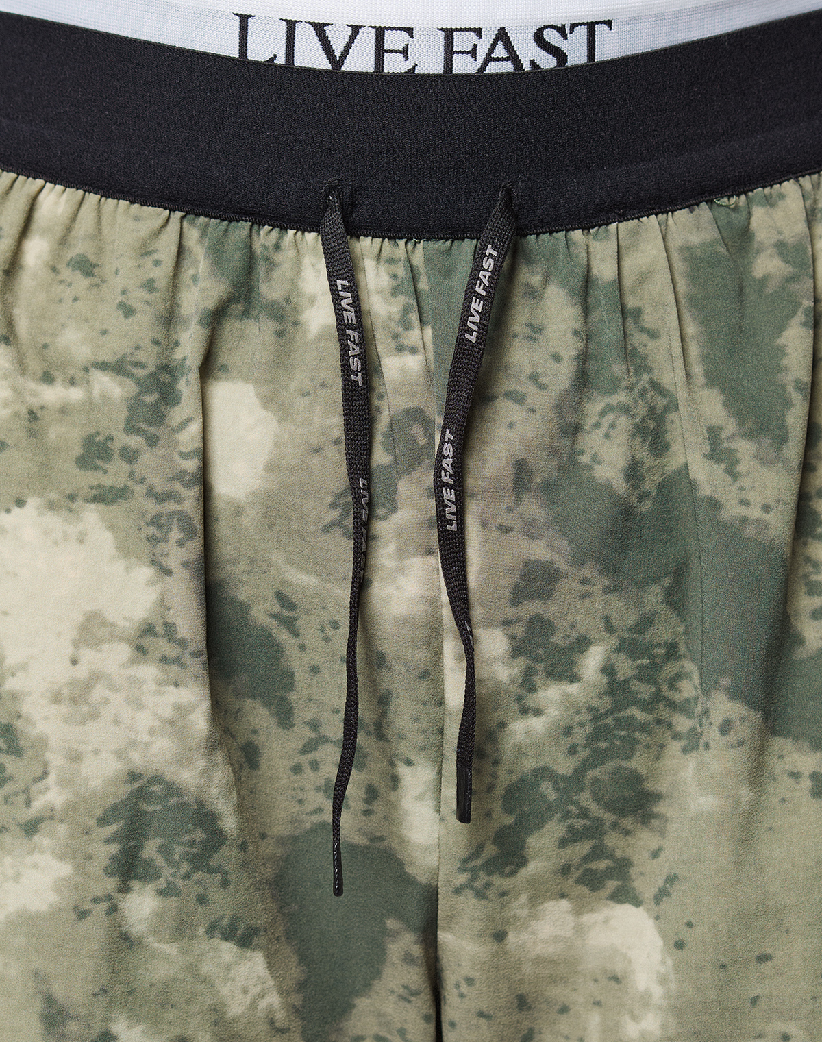 Close-up of the waistband and drawstrings of LFDY Performance Running Shorts by LIVE FAST DIE YOUNG. The black elastic waistband has a reflective LIVE FAST logo print in white, matching drawstrings, and offers a comfortable regular fit.
