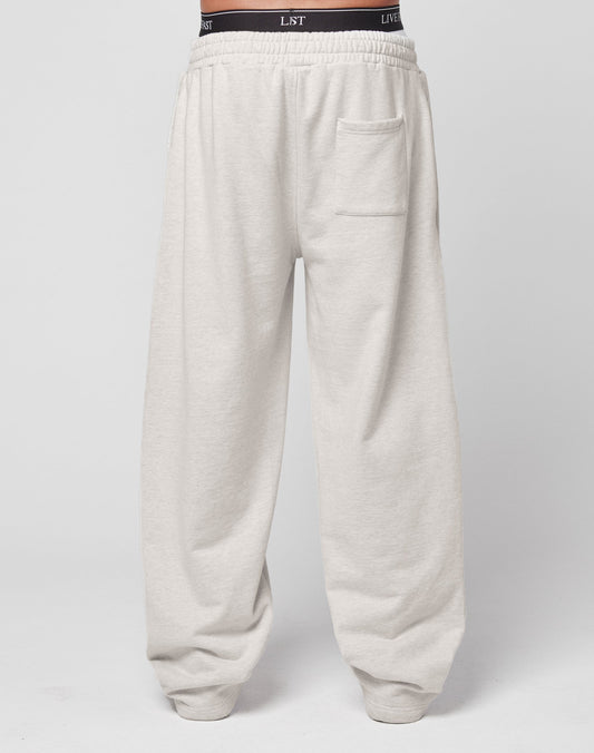 Die DY Jogger von LIVE FAST DIE YOUNG sind beige Sweatpants mit weitem Bein, Oversize Fit, elastischem Bund mit sichtbarem Text, rechter Gesäßtasche und entspannter Passform aus 100% Baumwolle.