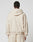 A person in an oversize fit, light beige LFDY Pleated Hooded Zip by LIVE FAST DIE YOUNG with Kapuze mit Kordel and matching sweatpants, made from soft Baumwolle, stands facing away against a plain light gray background.