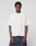 A man stands facing forward against a plain background, wearing the LIVE FAST DIE YOUNG LFDY Grand Theft Tee in white with front and back print, paired with dark blue jeans. The tee is made from 100% Baumwolle; his arms are relaxed at his sides.