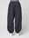 A person wears LIVE FAST DIE YOUNG's LFDY Performance Trackpants in black, featuring an oversize fit, 100% nylon material, elastic waistband and cuffs, and a zippered back pocket. White sneakers complete the look against a plain white background.