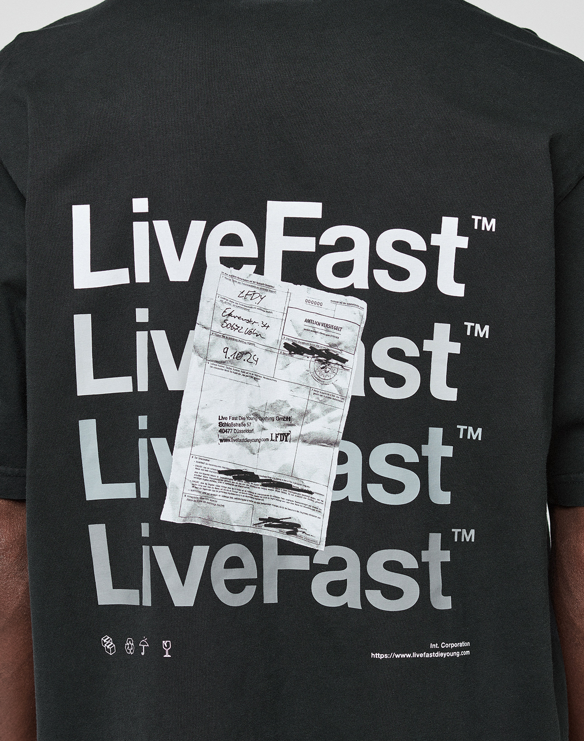 Back of the black Basic Evidence Tee by LIVE FAST DIE YOUNG with "LiveFast" four times in bold white, a crumpled receipt image over the text, small symbols, 100% Baumwolle, front/back print, and website link at the bottom.