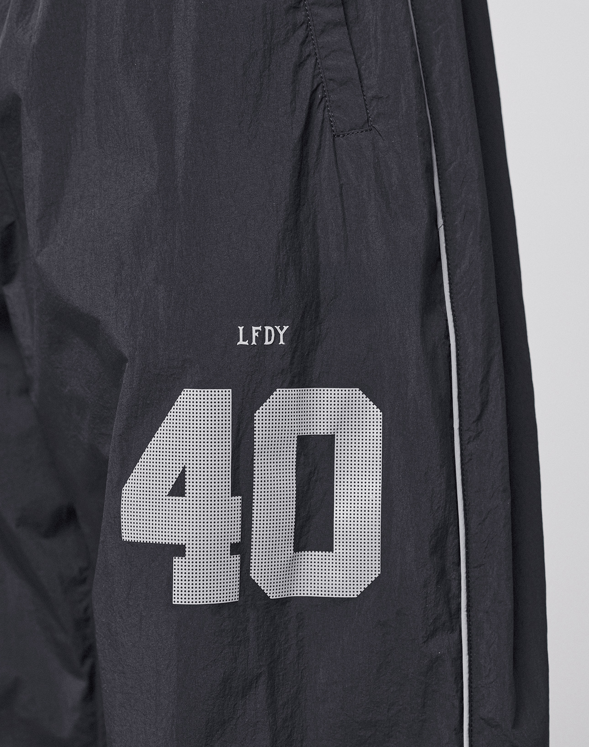 The LFDY Performance Trackpants by LIVE FAST DIE YOUNG feature black nylon fabric, white piping, and a reflective print. A white number 40 with "LFDY" above it appears on the left thigh for standout style.