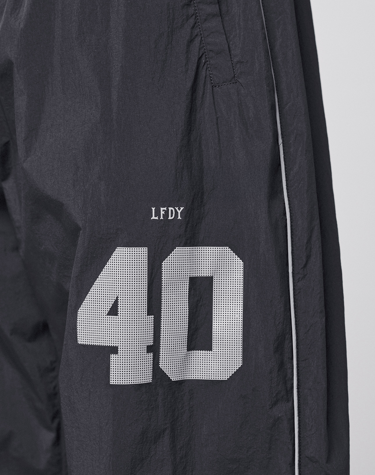The LFDY Performance Trackpants by LIVE FAST DIE YOUNG feature black nylon fabric, white piping, and a reflective print. A white number 40 with "LFDY" above it appears on the left thigh for standout style.